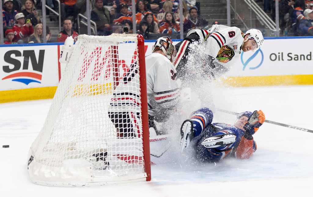 Chicago Blackhawks goalie Spencer Knight (30) makes the save as Sam Rinzel (6) and Edmonton Oilers' Trent Frederic (10) crash the net during the second period of an NHL game, in Edmonton on Thursday April 2, 2026. (Jason Franson/The Canadian Press via AP)