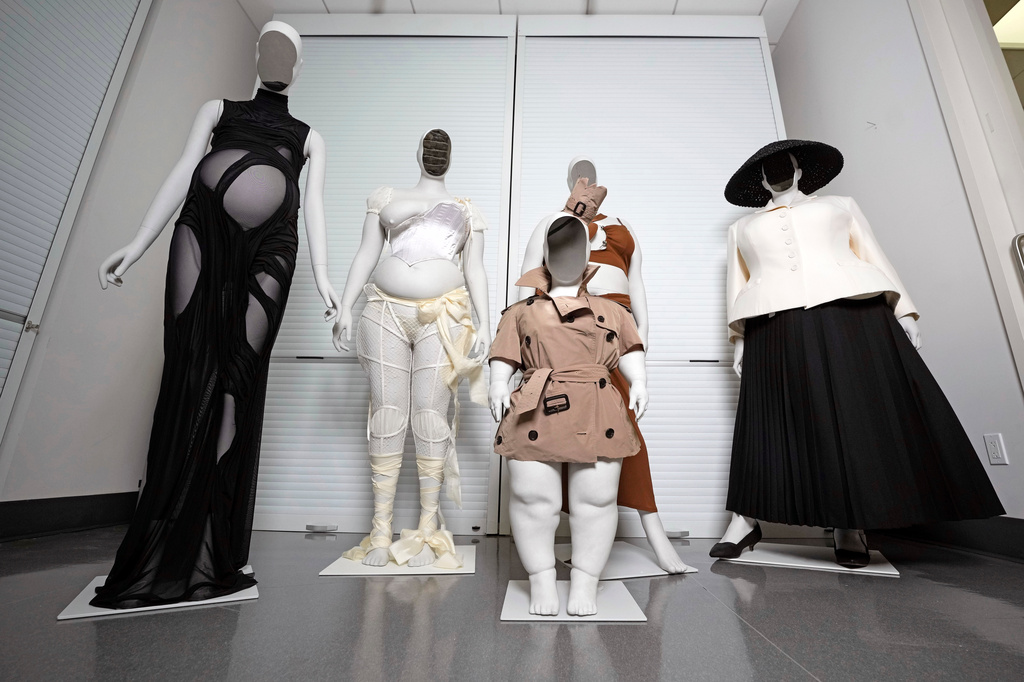 A Di Petsa dress by designer Dimitra Petsa appears on a pregnant mannequin, from left, an ensemble by Michaela Stark on a mannequin in Stark's image, a Burberry ensemble by Christopher Bailey on a mannequin image of Sinéad Burke, foreground, an ensemble by designer Karoline Vitto, on a mannequin model of Charlie Reynolds, and an outfit by designer Maria Grazia Chiuri for the House of Dior on a mannequin model of Yseult, are displayed in a room at the Metropolitan Museum of Art during preparations for the Met Gala exhibit "Costume Art" on Tuesday, April 14, 2026, in New York. (Photo by Charles Sykes/Invision/AP)