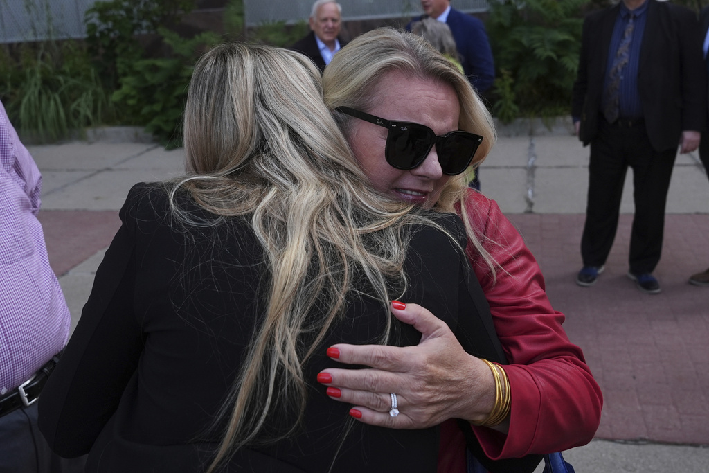 Meshawn Maddock receives a hug after a Michigan judge dismissed the criminal cases against 15 people accused of acting falsely as electors for President Donald Trump in the 2020 election Tuesday, Sept. 9, 2025 in Lansing, Mich. (AP Photo/Paul Sancya)