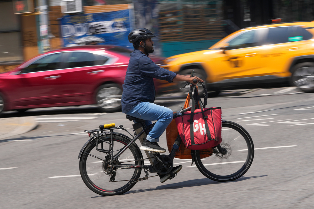 FILE - A delivery worker rides an electric bicycle in New York, July 25, 2023. (AP Photo/Seth Wenig)