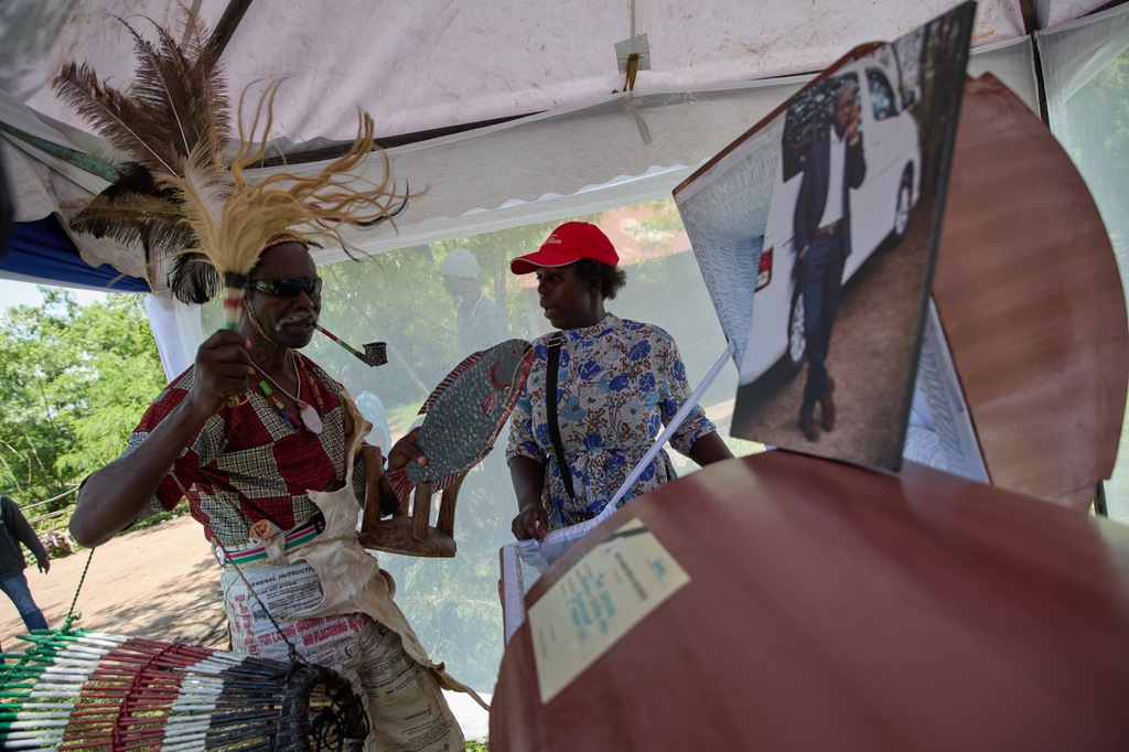 Professional mourner James Ajowi and a relative of the deceased stand in front of the coffin on the outskirts of Kisumu, Kenya, Friday, March 13, 2026. (AP Photo/Asa Wallin)