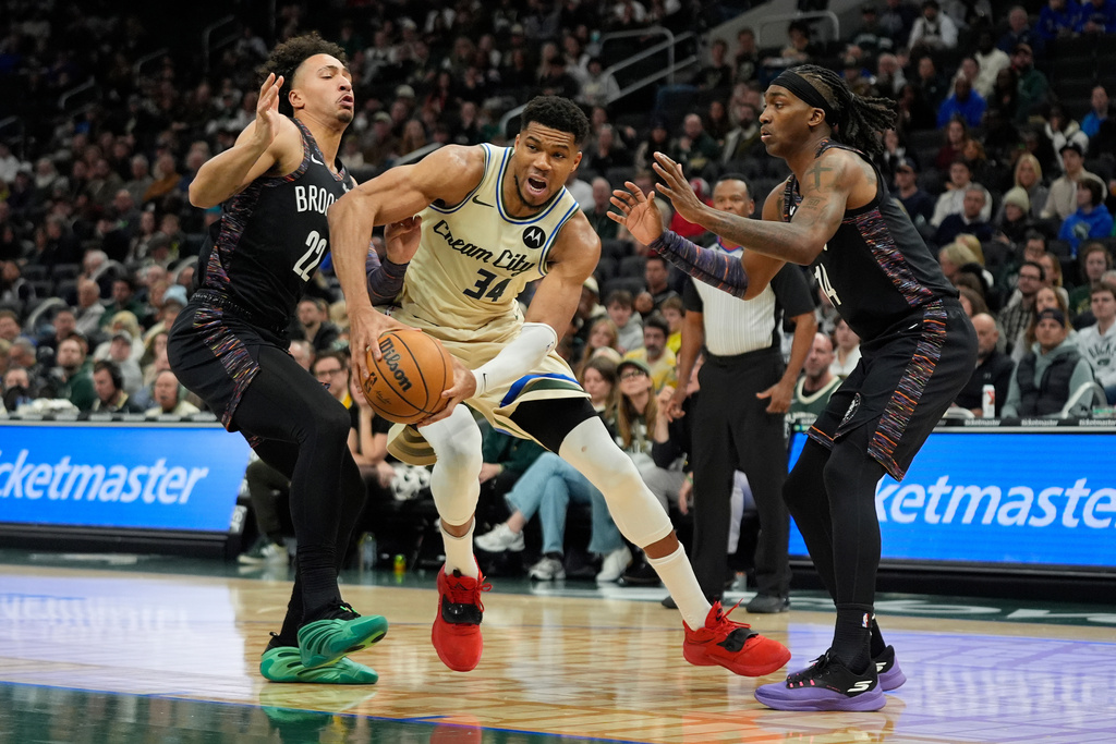 Milwaukee Bucks' Giannis Antetokounmpo (34) drives to the basket against Brooklyn Nets' Jalen Wilson (22) and Terance Mann (14) during the first half of an NBA basketball game Saturday, Nov. 29, 2025, in Milwaukee. (AP Photo/Aaron Gash)
