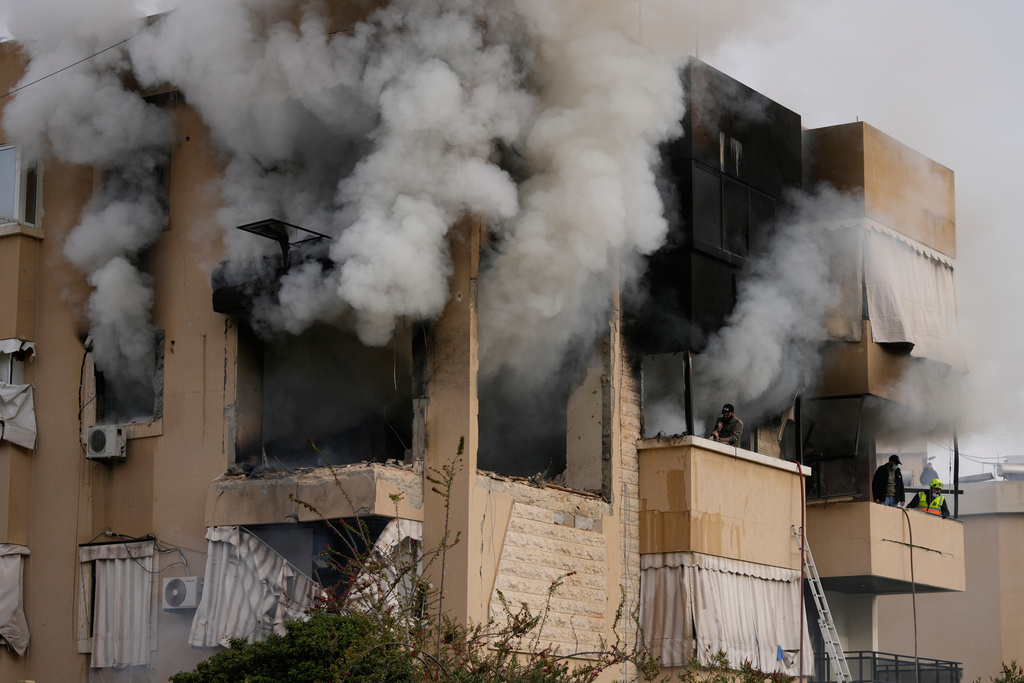 Rescue workers inspect an apartment damaged in an Israeli airstrike as thick smoke fills the building in the southern port city of Sidon, Lebanon, Saturday, March 14, 2026. (AP Photo/Mohammad Zaatari)