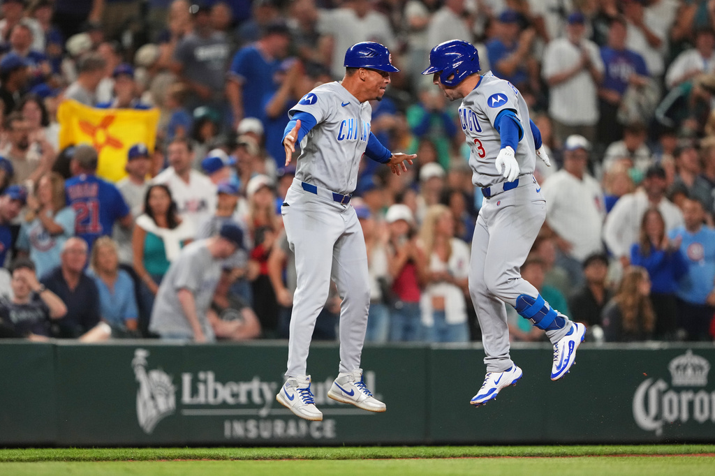 Chicago Cubs' Alex Bregman, right, celebrates with third base coach Quintin Berry after hitting a solo home run to tie the game during the ninth inning of a baseball game against the Seattle Mariners, Friday, Aug. 21, 2026, in Seattle. (AP Photo/Lindsey Wasson)