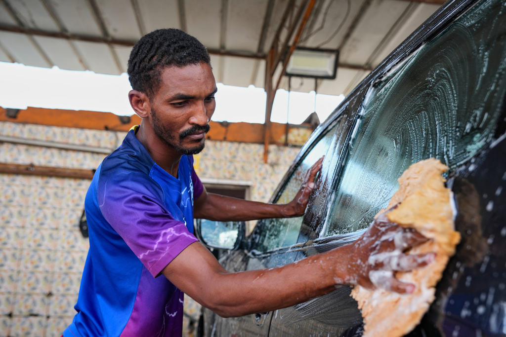Dicko Hamidou, a herder who fled his village in Burkina Faso, works at a car wash in Abidjan, Ivory Coast, Friday, Oct. 24, 2025. (AP Photo/Misper Apawu)