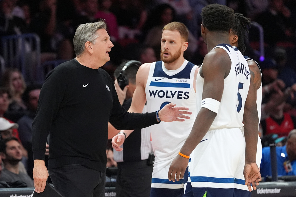 Minnesota Timberwolves head coach Chris Finch, left, talks with guards Donte Divincenzo, center, Anthony Edwards (5), and Bones Hyland, obscured, during the first half of an NBA basketball game against the Miami Heat, Saturday, Jan. 3, 2026, in Miami. (AP Photo/Rebecca Blackwell)