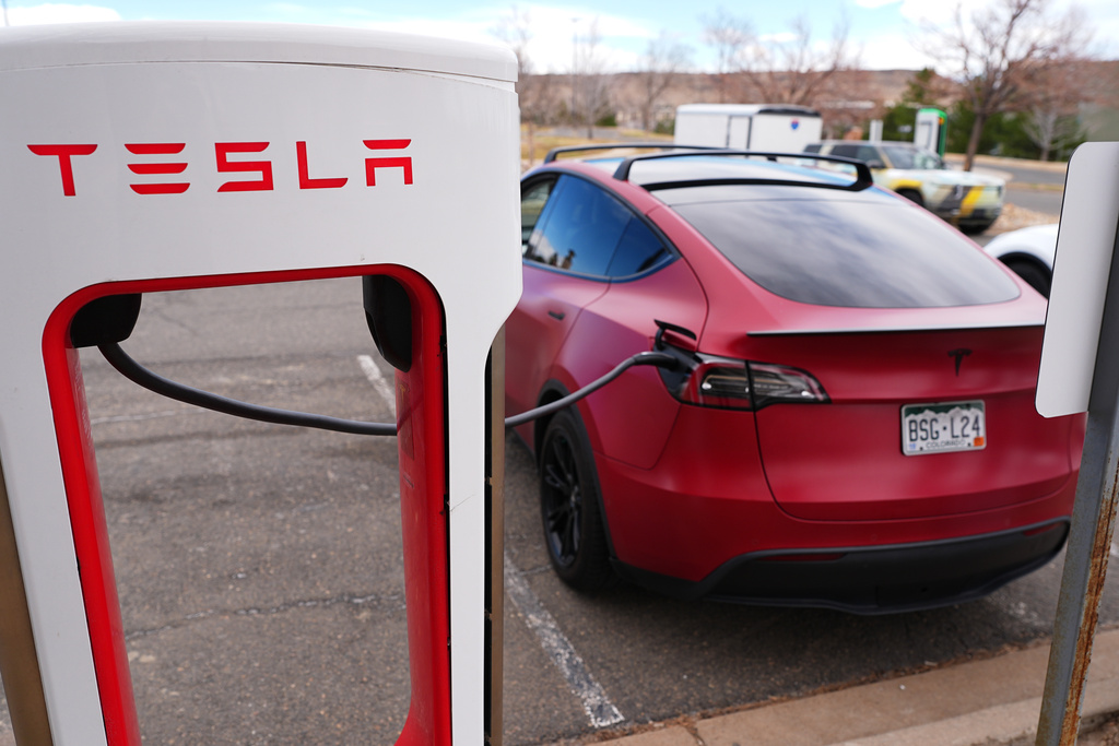 A motorist sits in a Tesla Model 3 at a Tesla charging station Friday, March 13, 2026, in Lakewood, Colo., in Denver. (AP Photo/David Zalubowski)