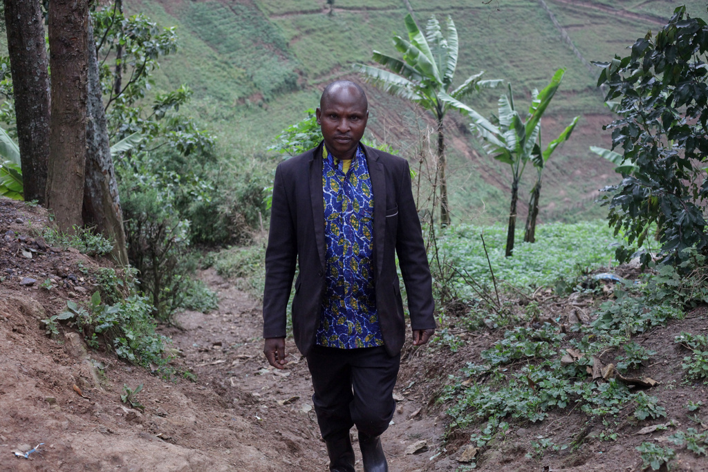 Philemon Mujuni, a reformed poacher, walks up a hill to his home at the foothill of Bwindi Impenetrable National Park in southwestern Uganda, Tuesday, Sept. 16, 2025. (AP Photo/Onen Patrick)