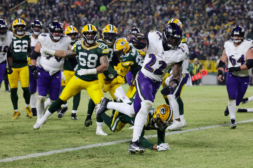 Baltimore Ravens running back Derrick Henry (22) scores a touchdown past Green Bay Packers cornerback Carrington Valentine (24) during the first half of an NFL football game, Saturday, Dec. 27, 2025, in Green Bay, Wis. (AP Photo/Matt Ludtke)