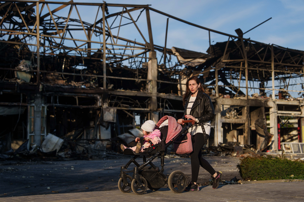 A woman pushes her baby in a stroller past a car workshop destroyed in a Russian attack in Zaporizhzhia, Ukraine, Wednesday, May 6, 2026. (AP Photo/Evgeniy Maloletka)