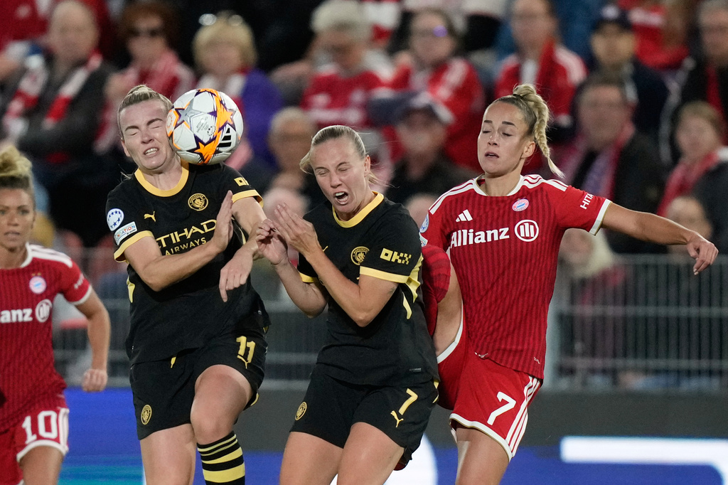 Bayern's Giulia Gwinn, right, collides with Manchester City's Beth Mead and Lauren Hemp, left, during the women's Champions League opening phase soccer match between FC Bayern Munich and Manchester City in Munich, Germany, Tuesday, Sept. 22, 2026. (AP Photo/Matthias Schrader)