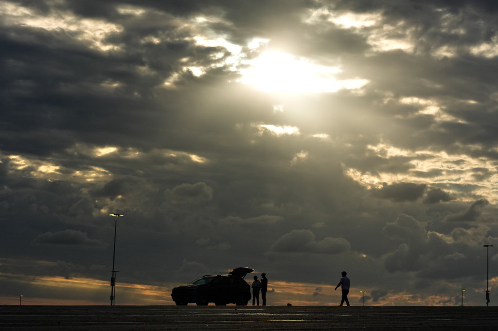 People gather under storm clouds in a parking lot outside Kauffman Stadium after a baseball game between the Kansas City Royals and the Chicago White Sox, Saturday, April 11, 2026, in Kansas City, Mo. (AP Photo/Charlie Riedel)