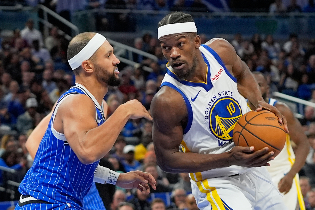 Golden State Warriors forward Jimmy Butler (10) drives around Orlando Magic guard Jalen Suggs during the second half of an NBA basketball game, Tuesday, Nov. 18, 2025, in Orlando, Fla. (AP Photo/John Raoux)