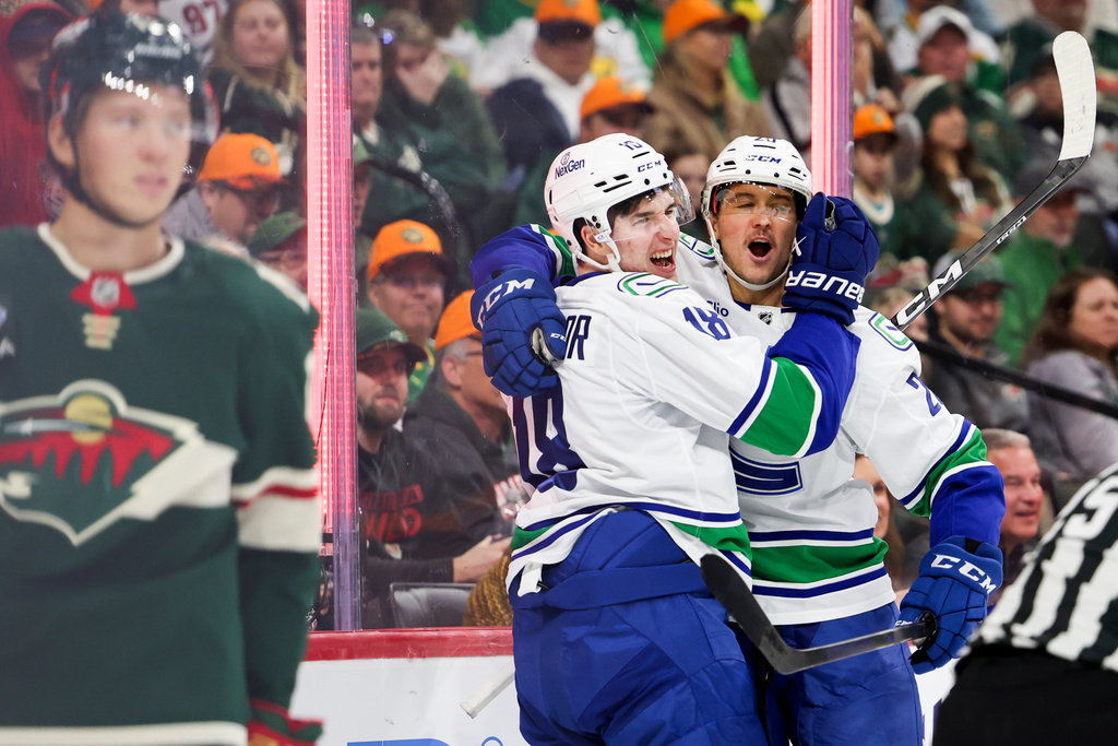 Vancouver Canucks left wings Drew O'Connor (18) and Mackenzie MacEachern (20) celebrate O'Connor's goal during the second period of an NHL hockey game against the Minnesota Wild, Saturday, Nov. 1, 2025, in St. Paul, Minn. (AP Photo/Ellen Schmidt)