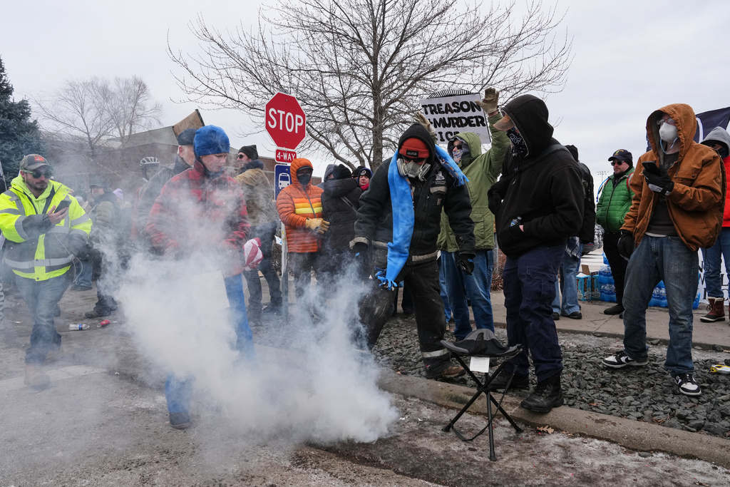 People cover tear gas deployed by federal immigration officers outside Bishop Henry Whipple Federal Building, Thursday, Jan. 15, 2026, in Minneapolis. (AP Photo/Adam Gray)