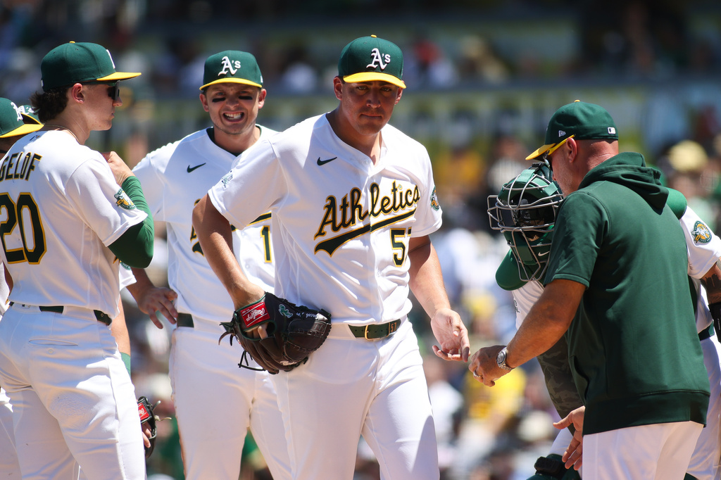 Athletics pitcher Jacob Lopez, centet, hands the ball to manger Mark Kotsay, right, after being pulled during the third inning of a baseball game against the New York Yankees, Sunday, May 31, 2026, in West Sacramento, Calif. (AP Photo/Scott Marshall)