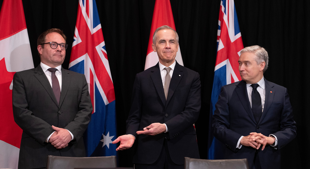 Canada's Prime Minister Mark Carney, center, gestures to Daniel Mulino, Australian Assistant Treasurer as he is introduced at the start of a signing ceremony, as Canada's Finance and National Revenue Minister Francois-Philippe Champagne, right, looks on, in Sydney, Australia, Wednesday, March 4, 2026. (Adrian Wyld/The Canadian Press via AP)