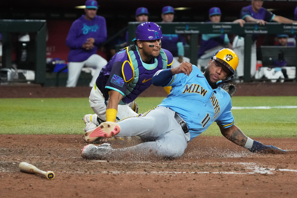 Milwaukee Brewers' Jackson Chourio (11) scores a run in front of Arizona Diamondbacks catcher Gabriel Moreno on a ball hit by Brice Turang in the eleventh inning of a baseball game, Friday, July 3, 2026, in Phoenix. (AP Photo/Rick Scuteri)