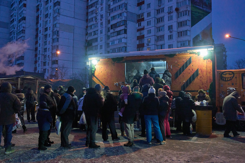 People stand in line for free hot meals that veterans of the 3rd Separate Assault Brigade of Ukraine's Armed Forces serve in residential neighborhood as repeated Russian air attacks on the country's energy sector leave people without power, heating and water in the harshest winter in decades in Kyiv, Ukraine, Sunday, Feb. 8, 2026. (AP Photo/Efrem Lukatsky)