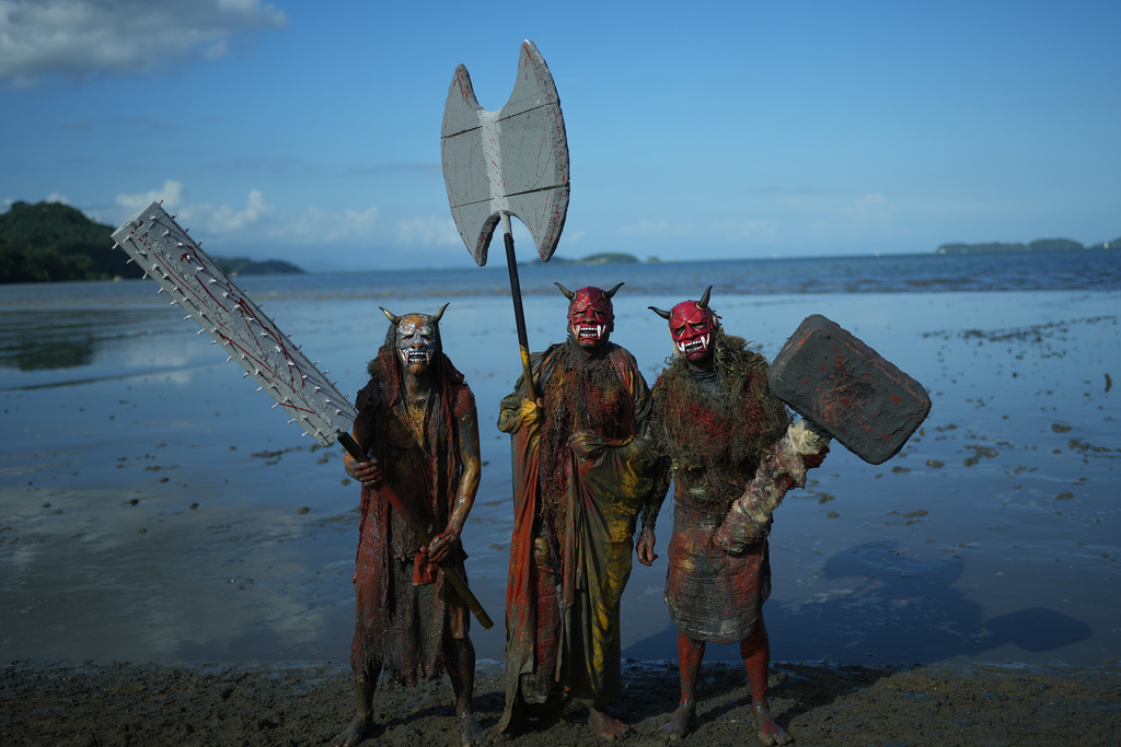Revelers pose in their customs on the shore during the Mud Block carnival party in Paraty, Brazil, Saturday, Feb. 14, 2026. (AP Photo/Andre Penner)