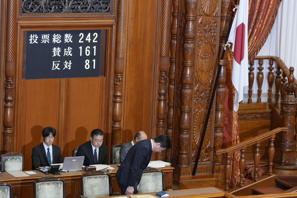 Japan's Chief Cabinet Secretary Minoru Kihara stands and bows to members of the House of Councillors beside a Japanese national flag after lawmakers passed a law prohibiting desecration of its national flag, during a parliamentary plenary session in Tokyo, Friday, July 17, 2026. (AP Photo/Eugene Hoshiko)