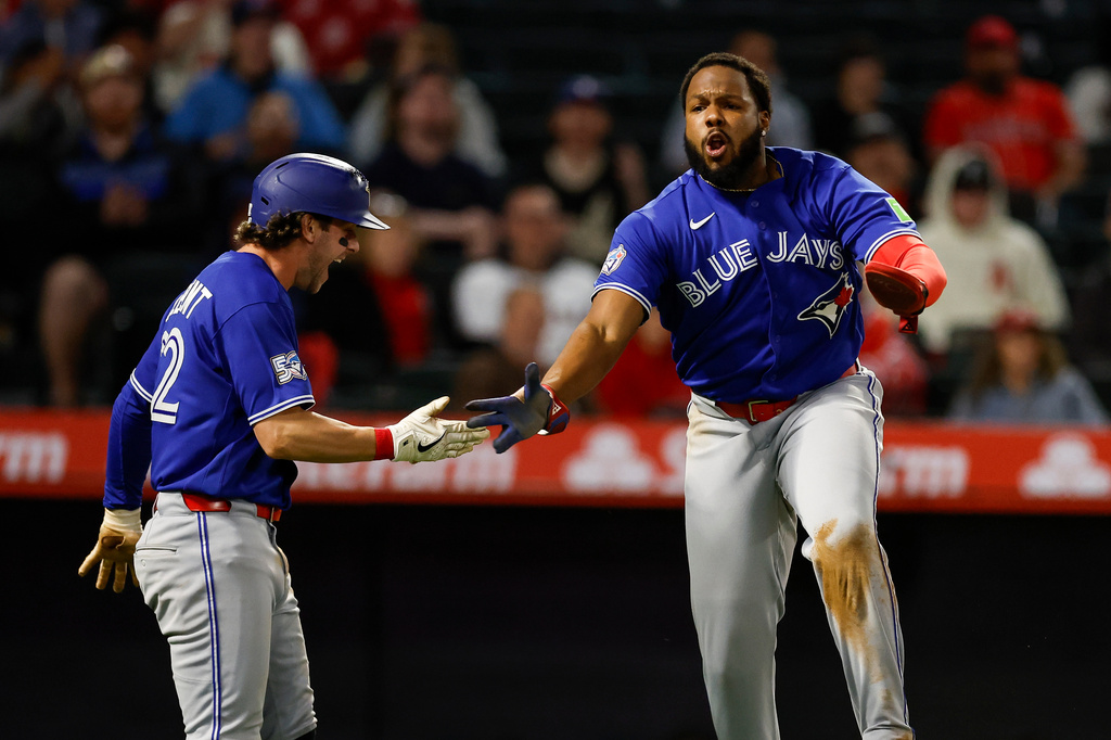 Toronto Blue Jays' Vladimir Guerrero Jr. (27) is greeted by Toronto Blue Jays' Ernie Clement (22) after scoring on a sacrifice fly from Toronto Blue Jays designated hitter Eloy Jimenez (74) during the eighth inning of a baseball game Tuesday, April 21, 2026, in Anaheim, Calif. (AP Photo/Caroline Brehman)
