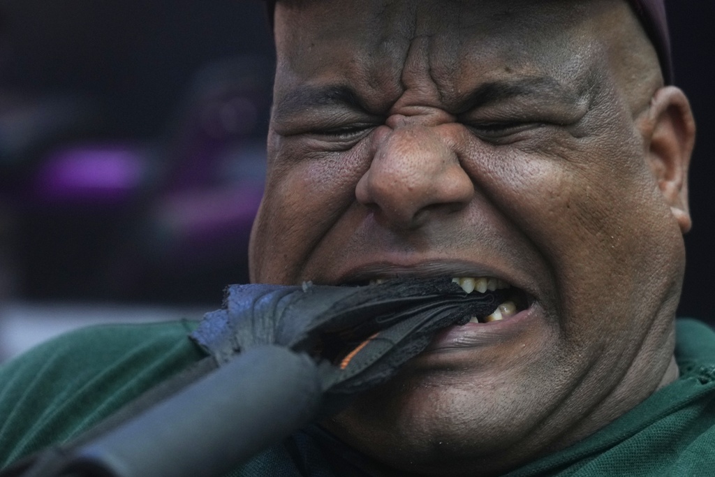 Egyptian wrestler Ashraf Mahrous, also known as Kabonga, pulls a heavy weight with his teeth during a training session at his gym in Cairo, Egypt, Tuesday, July 15, 2025. (AP Photo/Amr Nabil)