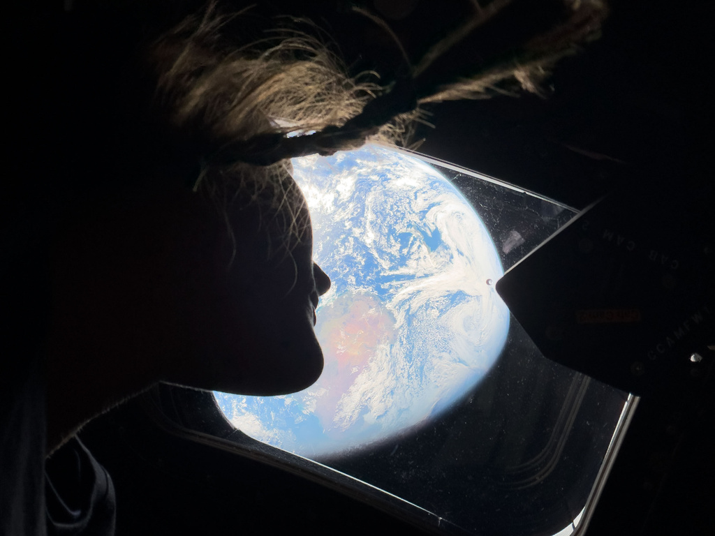This image provided by NASA, astronaut and Artemis II mission specialist Christina Koch peers out of one of the Orion spacecraft's main cabin windows, looking back at Earth, as the crew travels towards the Moon on Thursday, April 2, 2026. (NASA via AP)