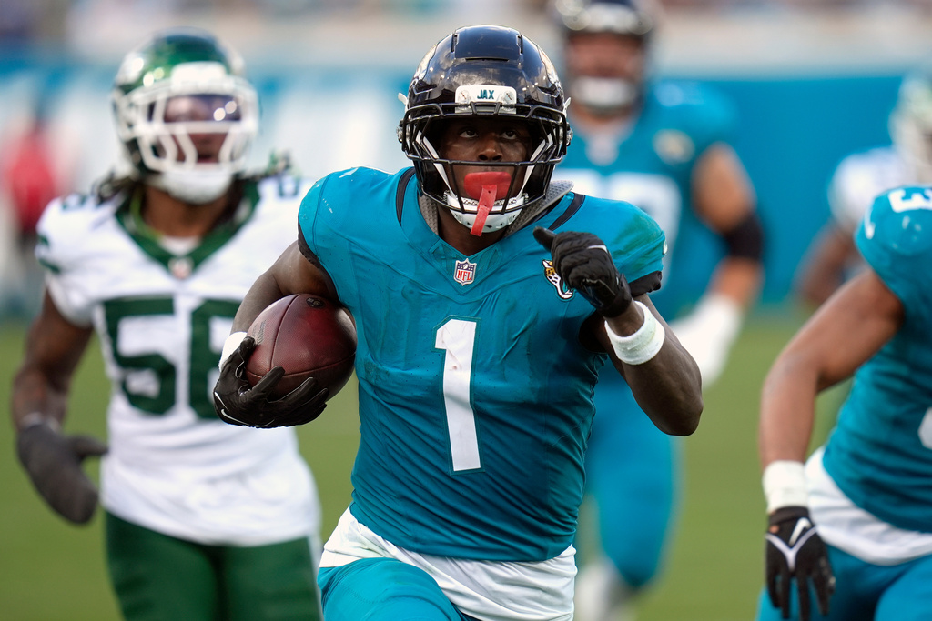 Jacksonville Jaguars running back Travis Etienne Jr. (1) runs for a touchdown against New York Jets linebacker Quincy Williams (56) during the second half of an NFL football game, Sunday, Dec. 14, 2025, in Jacksonville, Fla. (AP Photo/John Raoux)