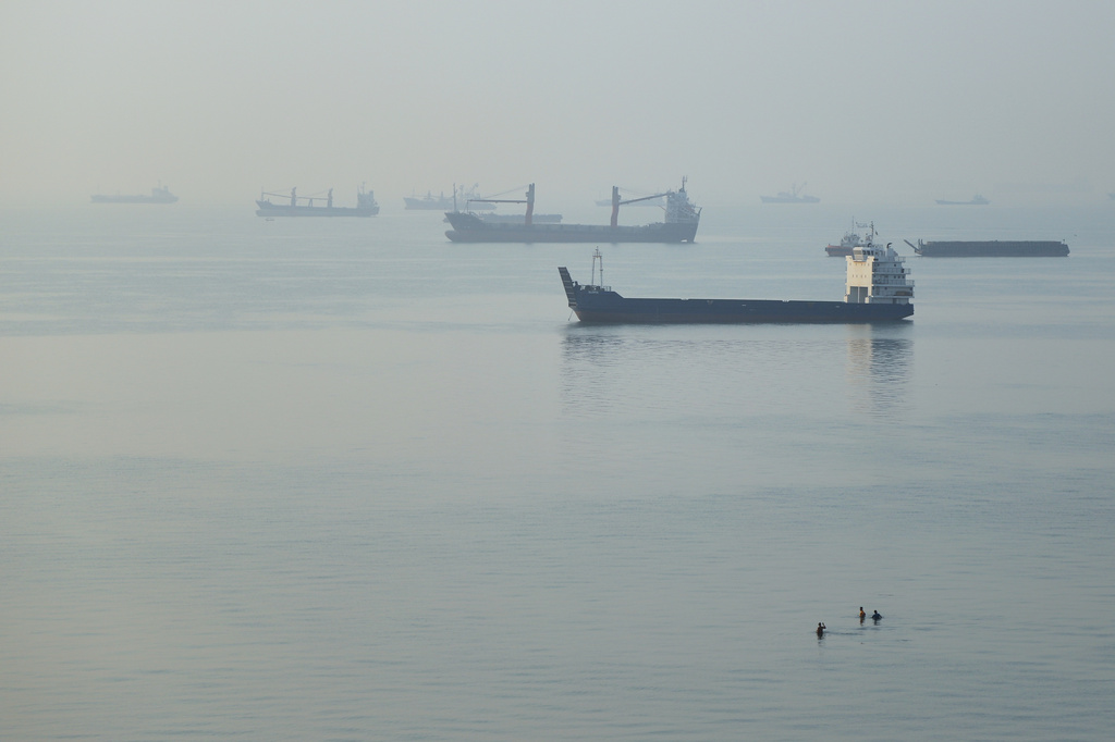 People wade in the water as cargo ships are anchored in the Strait of Hormuz off Bandar Abbas, Iran, early Monday, Sept. 28, 2026. (Amirhosein Khorgooi/ISNA via AP)