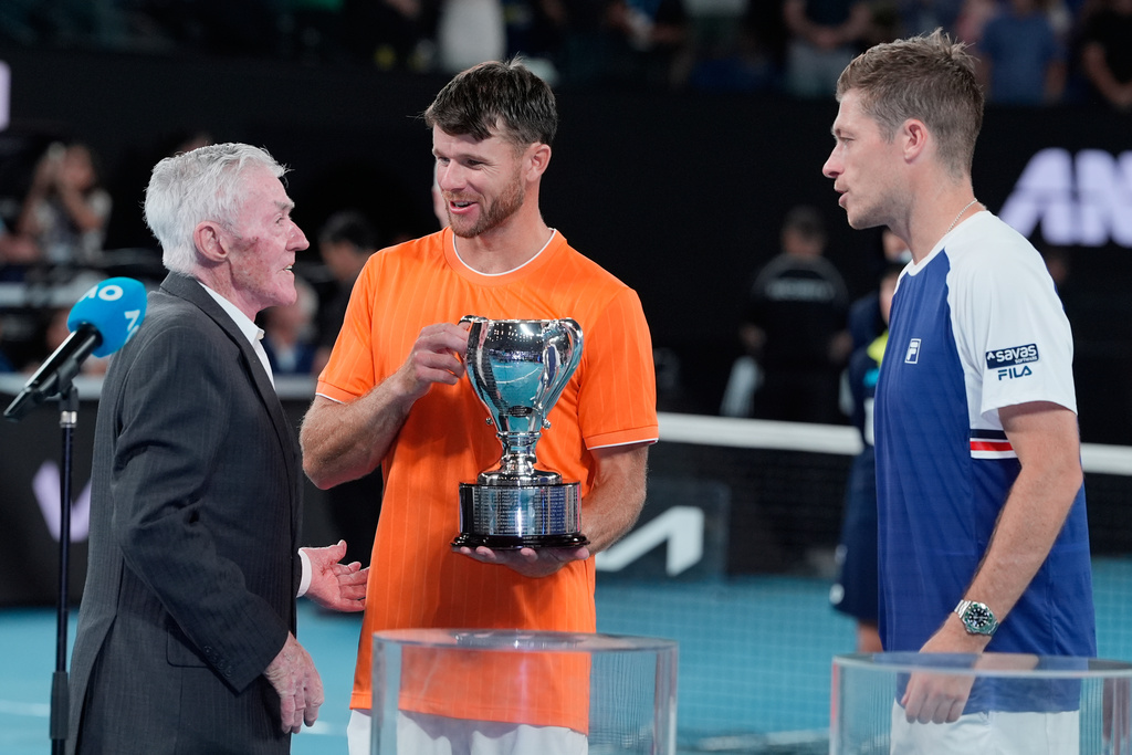 Ken Rosewall, left, presents the trophy to Christian Harrison of the U.S. and Neal Skupski, right, of Britain after they defeated Australia's Jason Kubler and Marc Polmans in the men's doubles final at the Australian Open tennis championship in Melbourne, Australia, Saturday, Jan. 31, 2026. (AP Photo/Asanka Brendon Ratnayake)