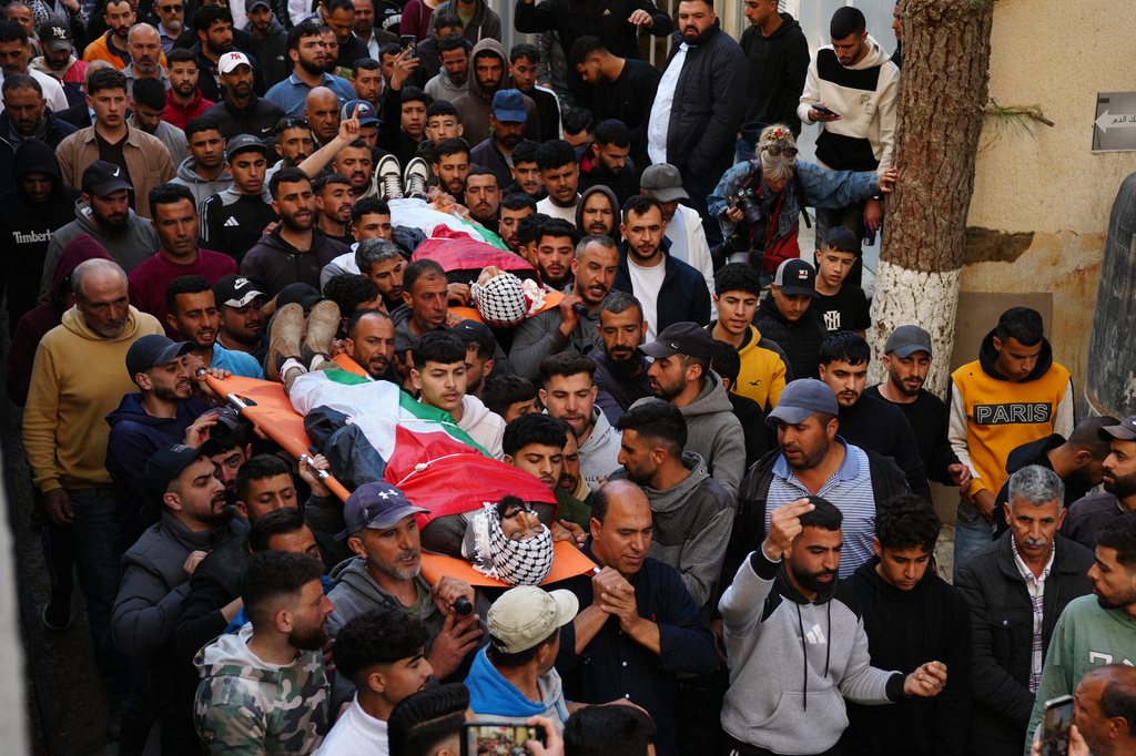 Mourners carry the bodies of Aws al-Na'san and Jihad Abu Naim, residents of the West Bank village of al-Mughayyir, out of the hospital's morgue in the West Bank city of Ramallah, Tuesday, April 21, 2026. (AP Photo/Mahmoud Illean)