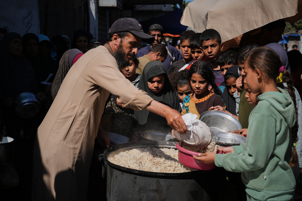 Palestinians receive donated food at a community kitchen in Deir al-Balah, central Gaza Strip, Thursday, Oct. 16, 2025. (AP Photo/Abdel Kareem Hana)