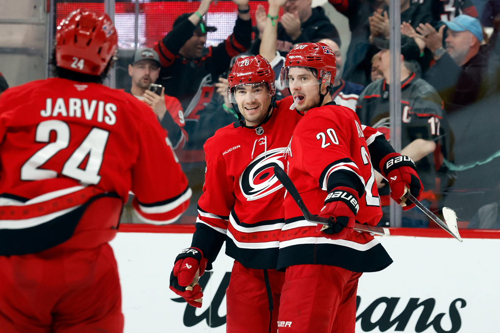 Carolina Hurricanes' Sean Walker, center, celebrates his game winning overtime goal with teammates Sebastian Aho (20) and Seth Jarvis (24) at an NHL hockey game against the Pittsburgh Penguins in Raleigh, N.C., Wednesday, March 18, 2026. (AP Photo/Karl DeBlaker)