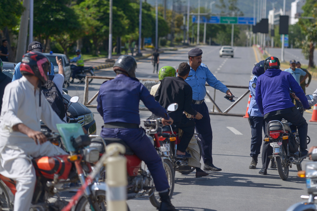 A police officer diverts motorcyclists at a barricaded road ahead of the second round of the U.S. Iran officials talks, in Islamabad, Sunday, April 19, 2026. (AP Photo/M.A. Sheikh)