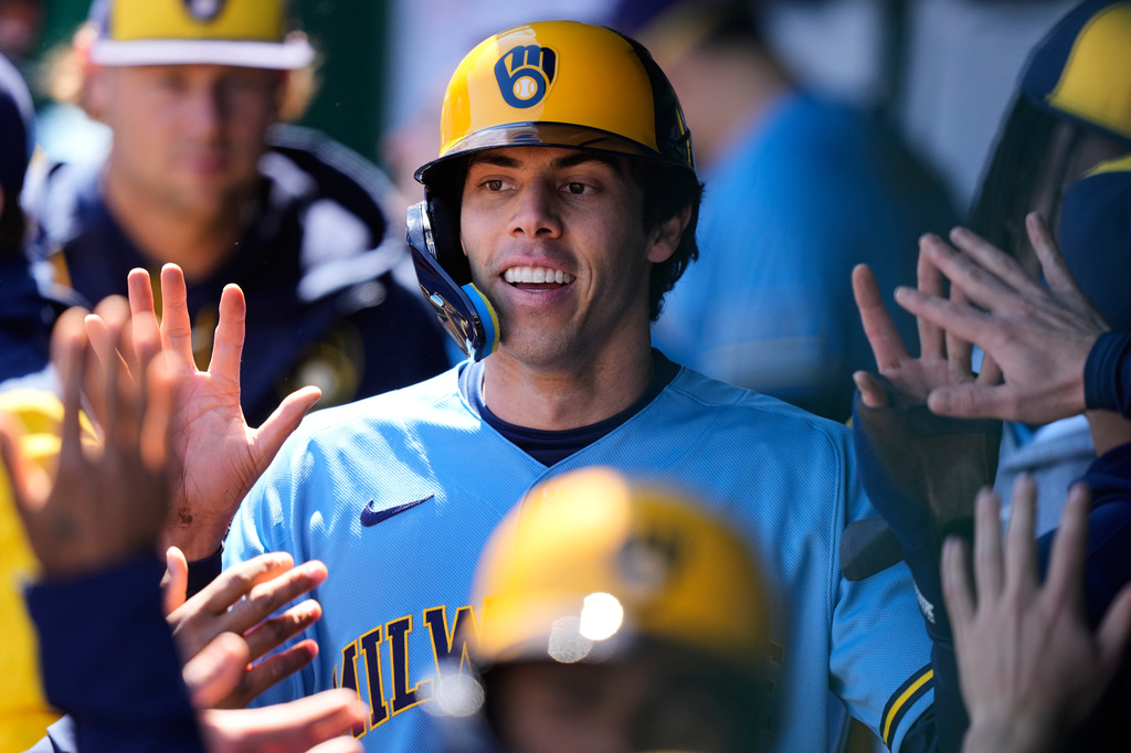 Milwaukee Brewers' Christian Yelich celebrates in the dugout after scoring on a double by Garrett Mitchell during the first inning in the first baseball game of a doubleheader against the Kansas City Royals, Saturday, April 4, 2026, in Kansas City, Mo. (AP Photo/Charlie Riedel)
