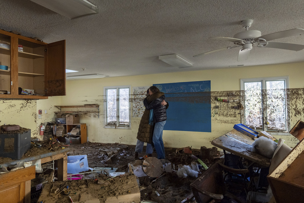 Nicole Schoychid, left, and Rebekah Canu, co-founders of Wildwood Agile Leaning Center, embrace inside the schoolhouse, which was damaged by flooding in Hurricane Helene, as they are surrounded by debris and mud, Thursday, Dec. 5, 2024, in Boone, N.C. The school had to compete against many other organizations and businesses vying for their own space in Boone after Helene damaged the town, creating a “bottleneck” from demand, Schoychid says. (AP Photo/Stephanie Scarbrough)