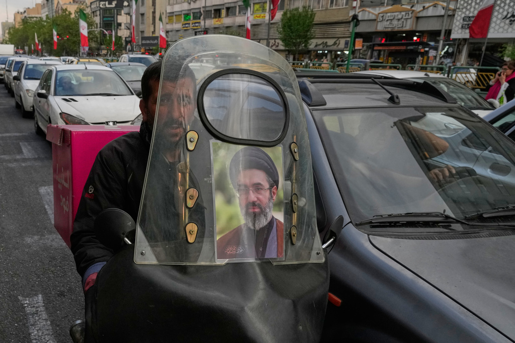 A man drives his motorbike with a poster on its windshield depicting Iran's Supreme Leader Ayatollah Mojtaba Khamenei in downtown Tehran, Iran, Monday, April 13, 2026. (AP Photo/Vahid Salemi)