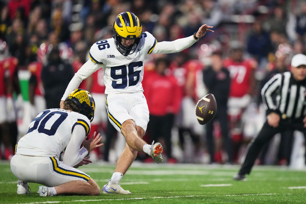 Michigan kicker Dominic Zvada (96), with punter Hudson Hollenbeck (90) holding, kicks an extra point during the first half of an NCAA college football game against Maryland, Saturday, Nov. 22, 2025, in College Park, Md. (AP Photo/Stephanie Scarbrough)