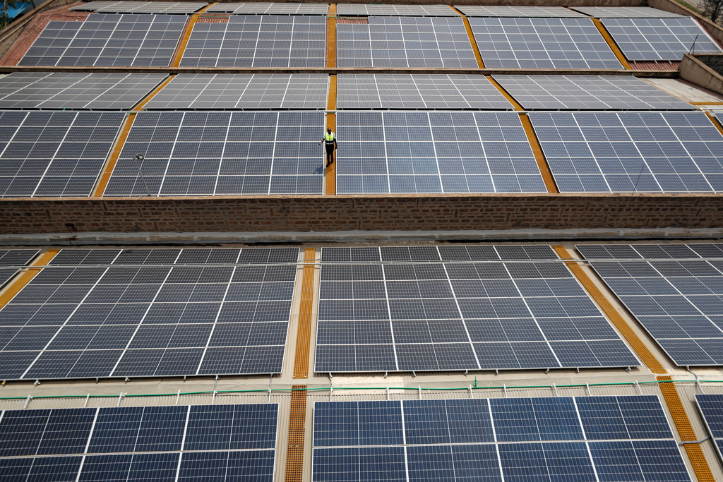 FILE - Mark Munyua, CP solar's technician, examines solar panels on the roof of a company in Nairobi, Kenya, Sept. 1, 2023. (AP Photo/Brian Inganga, File)