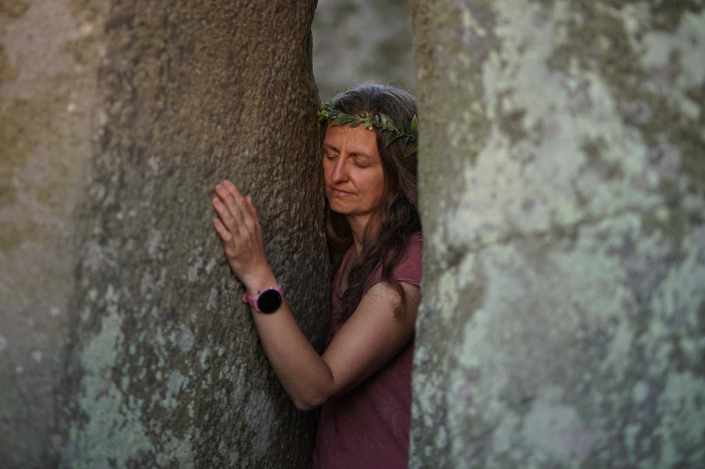 A reveler touches a stone at the ancient stone circle Stonehenge to celebrate the summer solstice, the longest day of the year, near Salisbury, England, on Saturday, June 20, 2026. (AP Photo/Alberto Pezzali)
