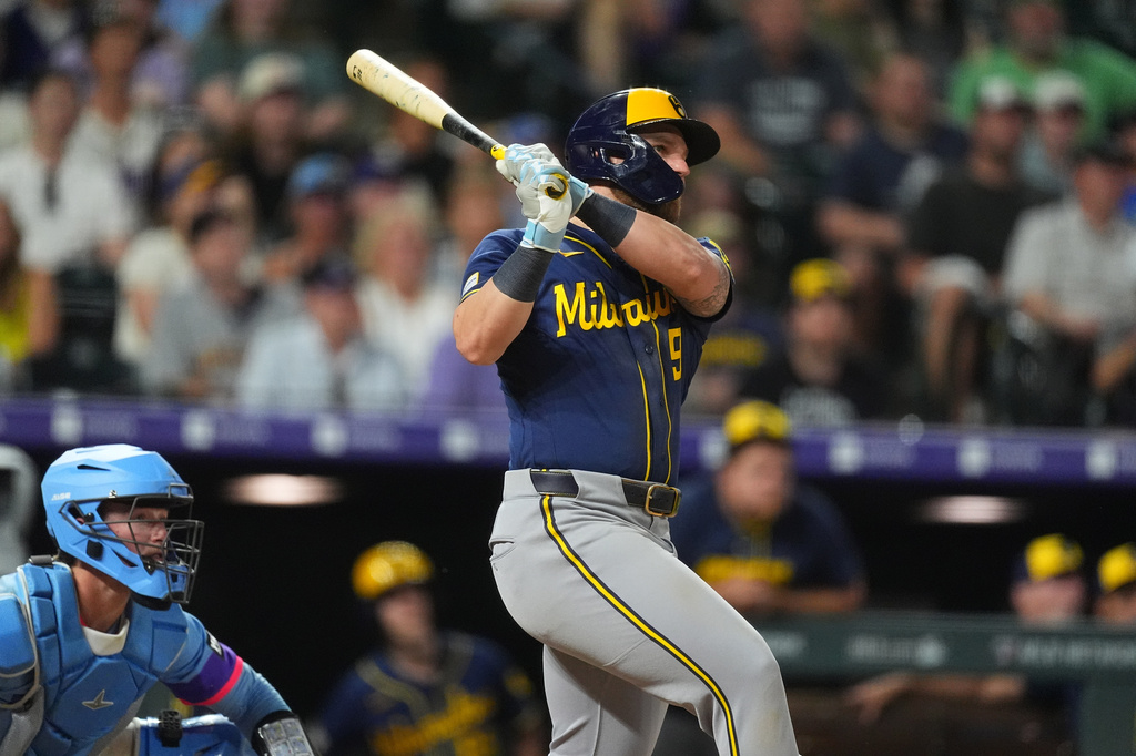 Milwaukee Brewers' Jake Bauers, right, follows the flight of his double that drove in two runs off Colorado Rockies relief pitcher Juan Mejia in the 10th inning of a baseball game Friday, June 5, 2026, in Denver. (AP Photo/David Zalubowski)