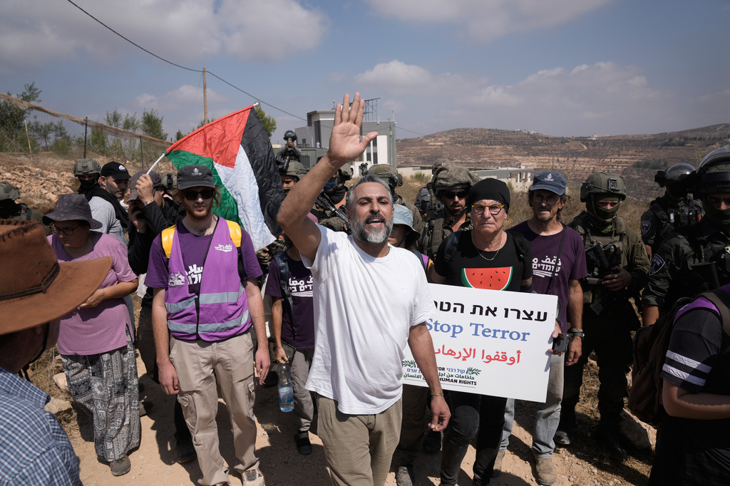 Activists march with food and water supplies toward the houses of three Palestinian families that have been besieged by Israeli settlers for six days, in the occupied West Bank village of Qusra, south of Nablus, Friday, Aug. 14, 2026. (AP Photo/Majdi Mohammed)