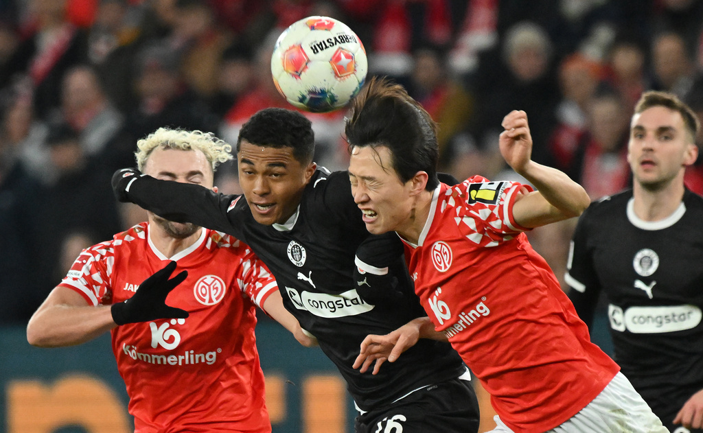 St. Pauli's Joel Chima Fujita, centre, Mainz's Jae-sung Lee and Mainz's Benedict Hollerbach, left, fight for the ball during the Bundesliga soccer match between FSV Mainz 05 and FC St. Pauli, in Mainz, Germany, Sunday Dec. 21, 2025. (Torsten Silz/dpa via AP)