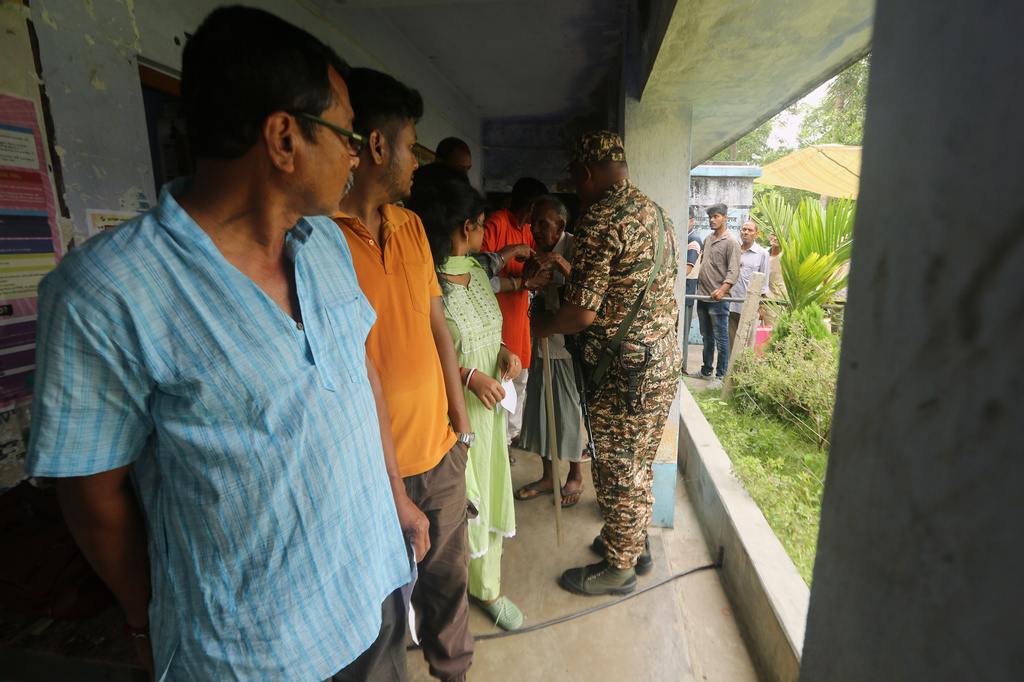 A security person assists voters standing in a queue at a polling booth during the first phase of voting in West Bengal state elections in Nandigram, India, Thursday, April 23, 2026. (AP Photo/Bhaskar Mallick)