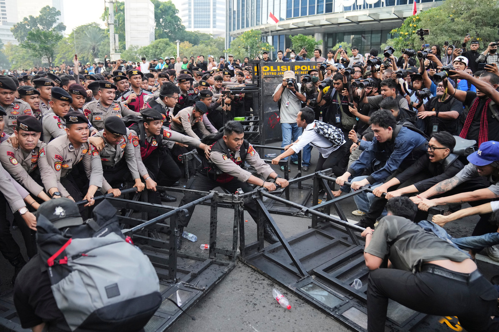 Student protesters tear down a police barricade during a rally against a fuel price hike, government inefficient spendings, and military involvement in civilian affairs in Jakarta, Indonesia, Friday, June 12, 2026. (AP Photo/Dita Alangkara)