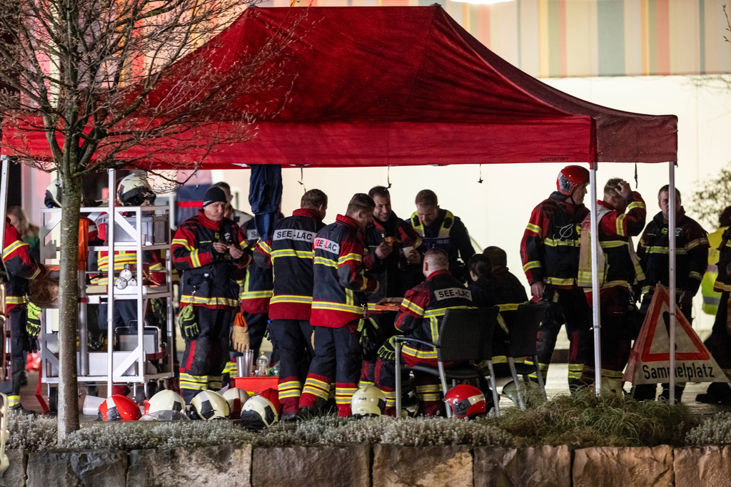 Firemen gather next to the charred shell of a postal bus, not pictured, which caught fire killing several people and injuring others, in Kerzers, Switzerland, Tuesday, March 10, 2026. (Alessandro della Valle/Keystone via AP)