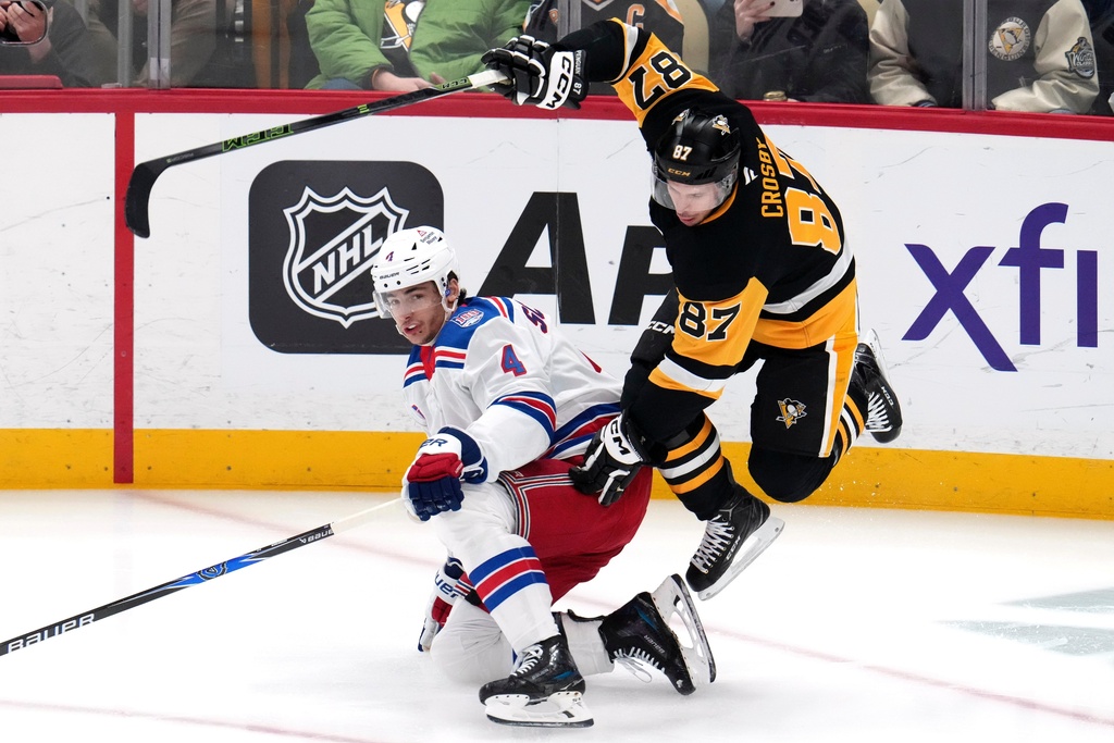 Pittsburgh Penguins' Sidney Crosby (87) leaps over New York Rangers' Braden Schneider (4) during the first period of an NHL hockey game in Pittsburgh, Saturday, Jan. 31, 2026. (AP Photo/Gene J. Puskar)