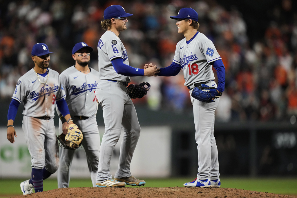 Los Angeles Dodgers starting pitcher Yoshinobu Yamamoto (18) shakes hands with first baseman Enrique Hernandez (8) before leaving the mound during a pitching substitution in the ninth inning of a baseball game against the Baltimore Orioles, Saturday, Sept. 6, 2025, in Baltimore. (AP Photo/Stephanie Scarbrough)