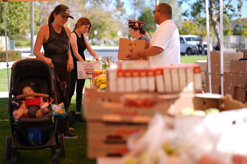 Elana Peck, back, who's husband is active duty Marine, stands on line to receive food during a Feeding San Diego food distribution for military families affected by the federal shutdown Friday, Nov. 7, 2025, in Oceanside, Calif. (AP Photo/Gregory Bull)